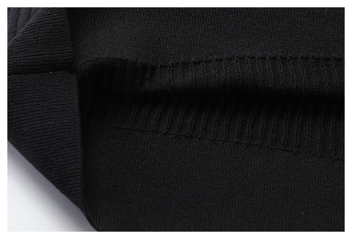 Close-up of black rib-knit garment fabric with a horizontal seam and ribbed edge.