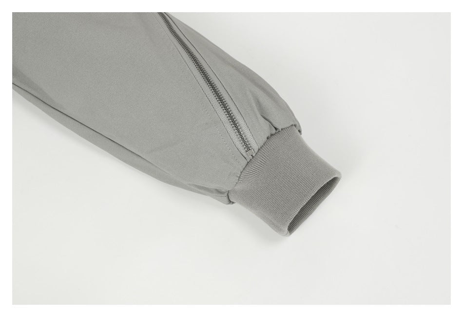 Close-up of a gray jacket sleeve with a zipper and ribbed cuff.