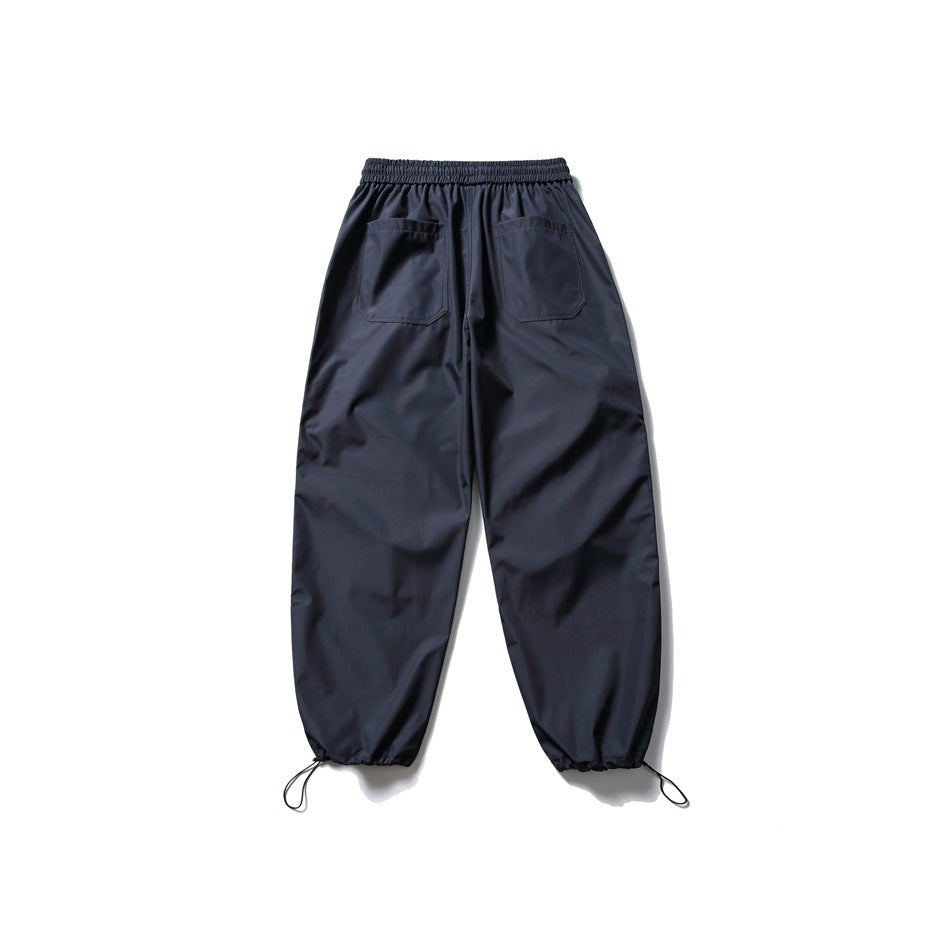 Rear view of navy jogger pants with an elastic waist, two back pockets, and drawcords at the cuffs.