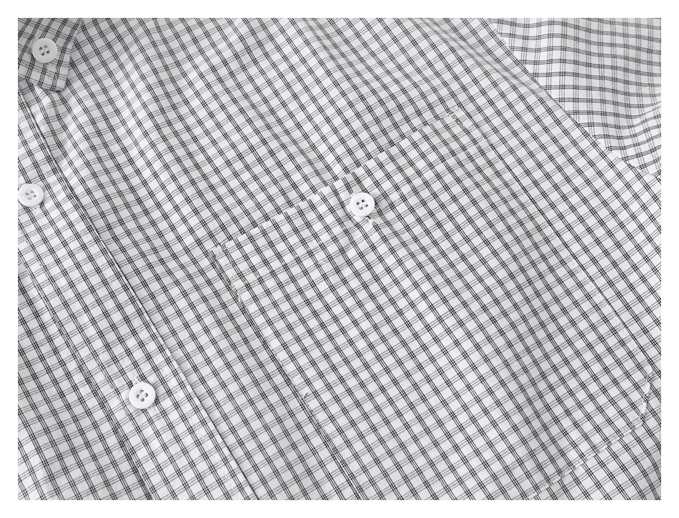 Close-up of the front chest pocket and button placket on a white shirt with a fine black grid plaid.