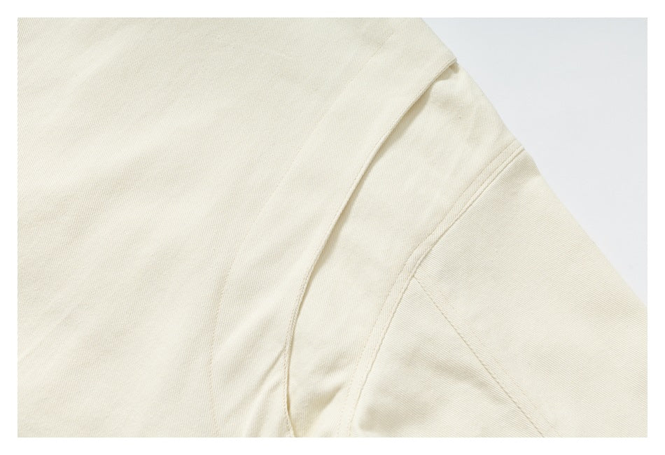Close-up of a cream jacket shoulder and sleeve seam with visible topstitching.