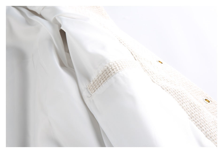View inside an ivory jacket, showing smooth pale lining, a textured seam panel, and metal snap hardware.