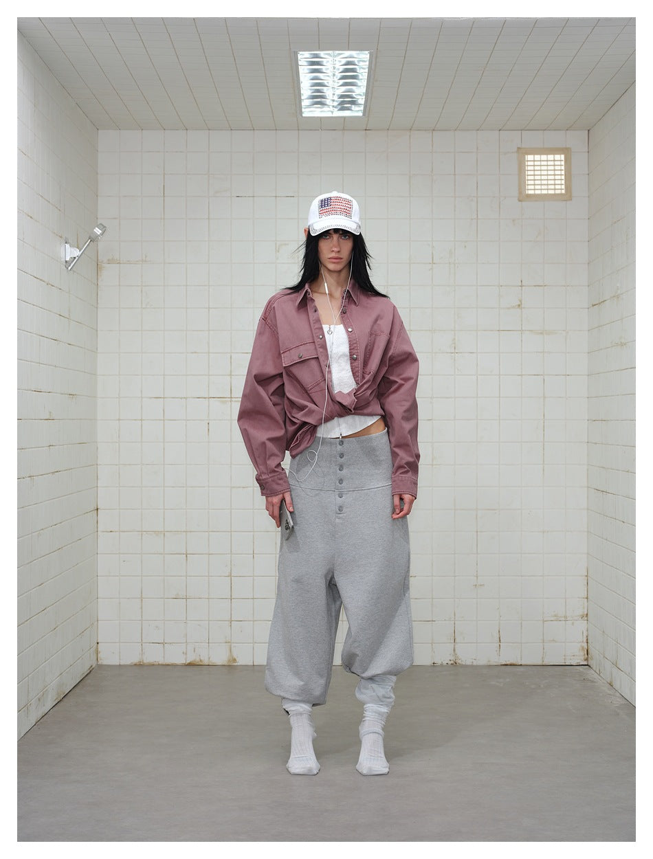 Model wearing the dusty red shirt knotted at the front over a white top with gray pants and a white cap