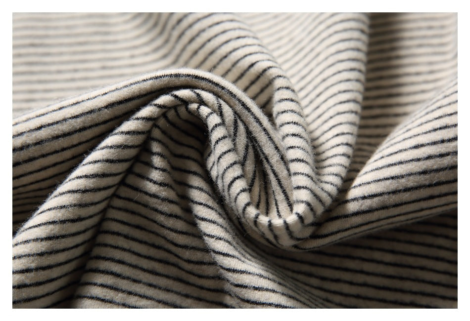 Close-up of softly gathered cream fabric with thin black horizontal stripes.