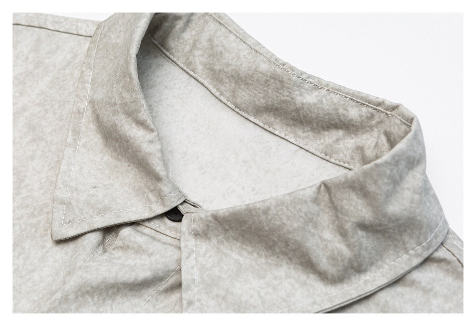 Close-up of the light gray shirt's pointed collar, stitching, and top button.