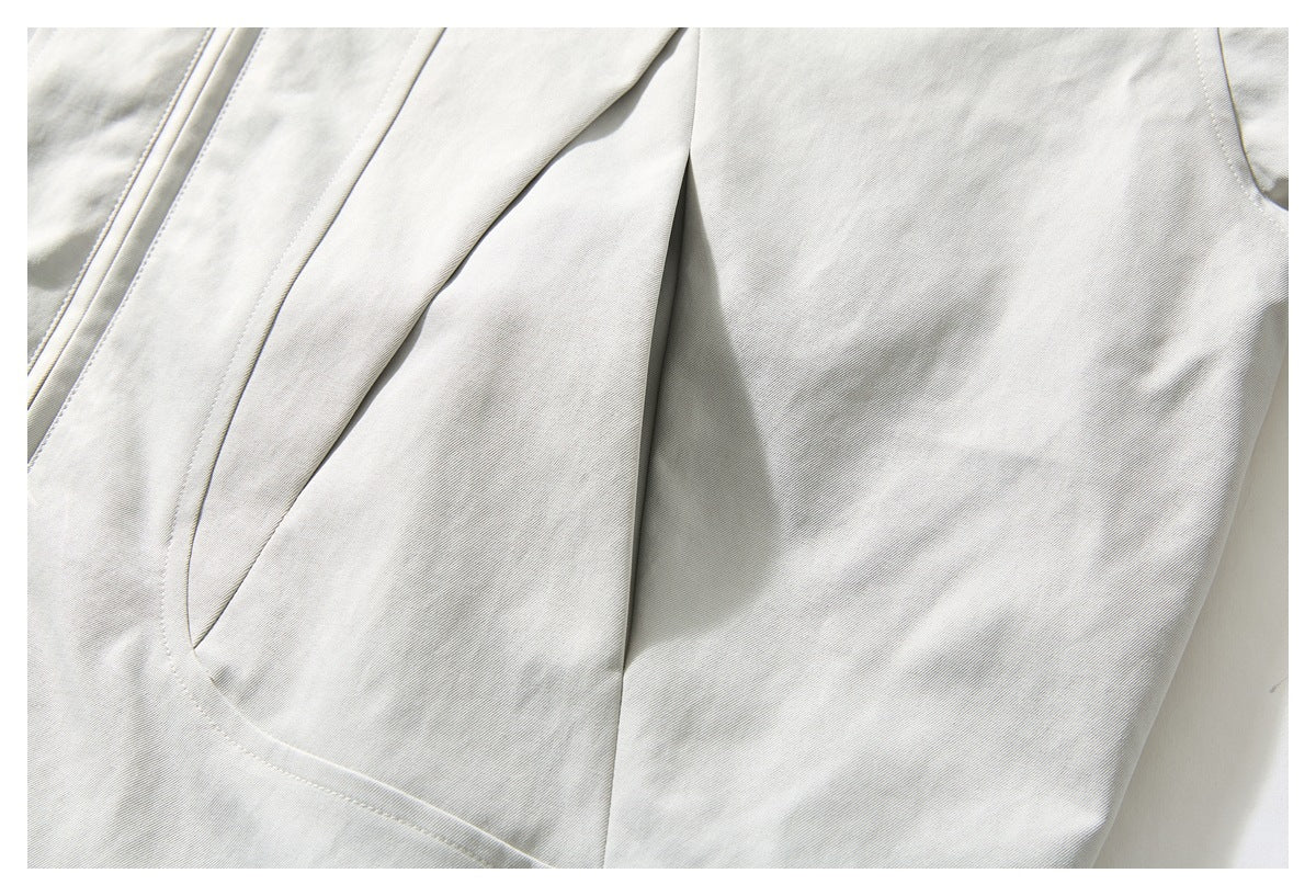 Close-up of an off-white jacket's curved pocket opening and stitched panel seams.