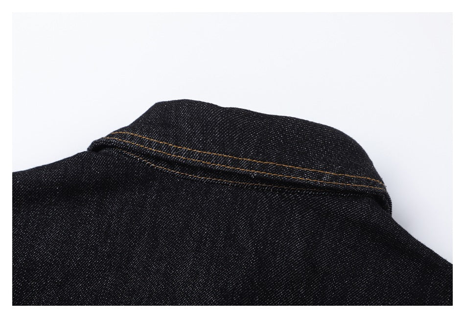 Close-up of the back collar and orange double stitching on a black denim jacket.