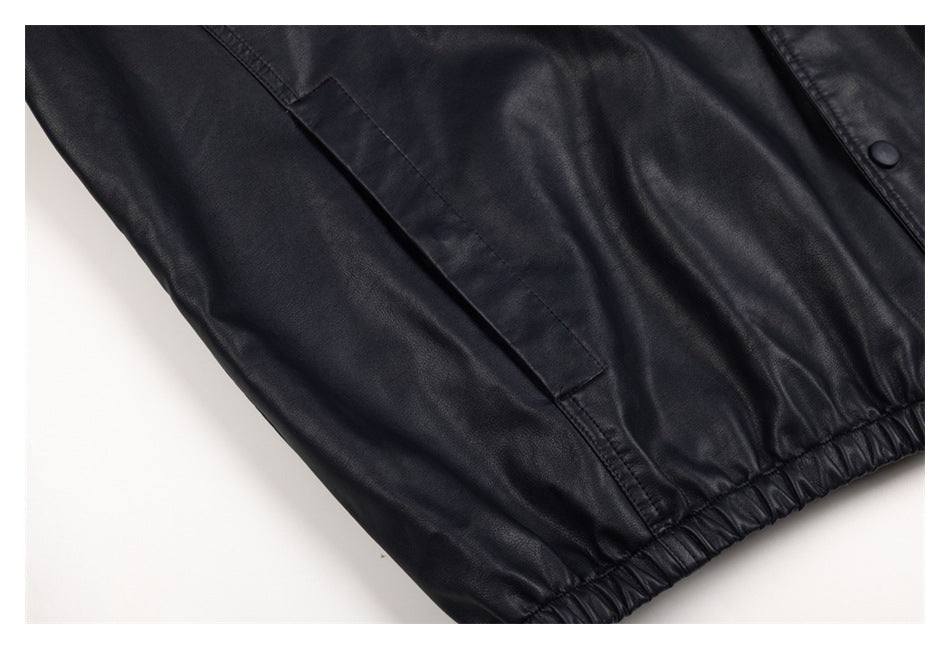 Close-up of a side pocket, stitching and elasticated hem on the black jacket.