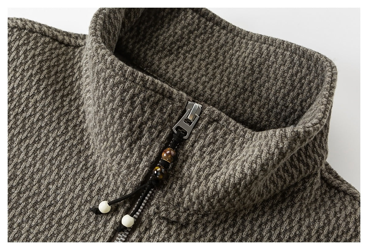 Close-up of a gray-brown textured garment collar with a metal zipper and decorative bead pulls.