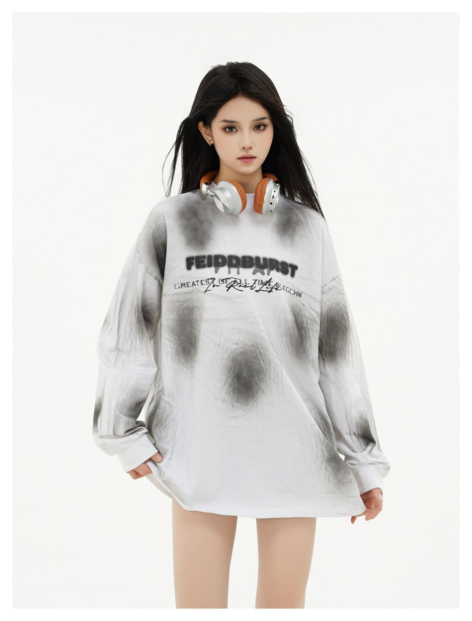 Closer view of a model wearing an oversized white and gray tie-dye shirt with black chest lettering.