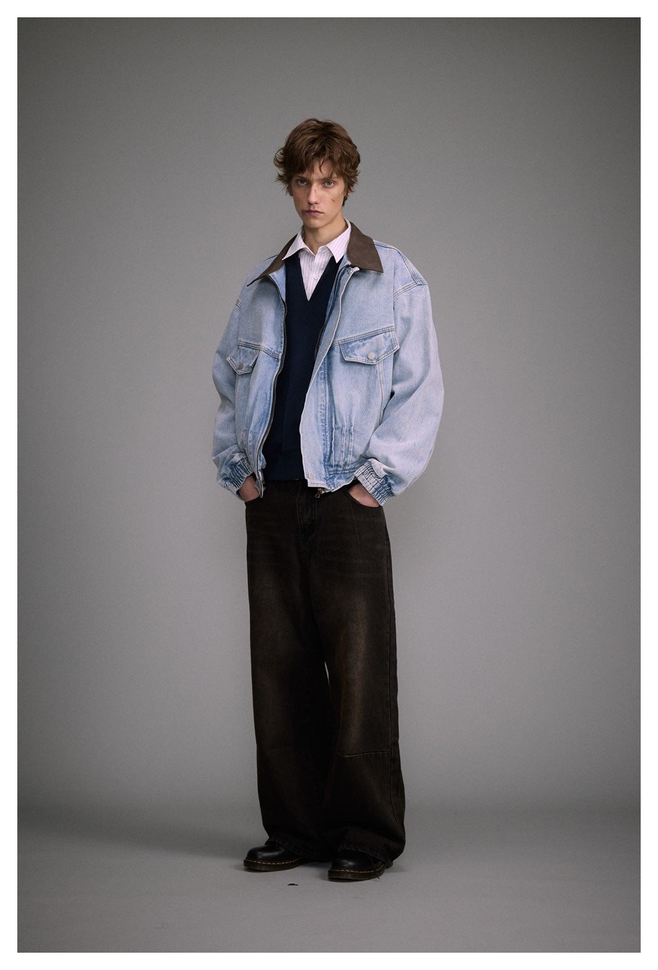 Full-length front view of a model wearing a light blue denim jacket with a brown collar and loose dark trousers.
