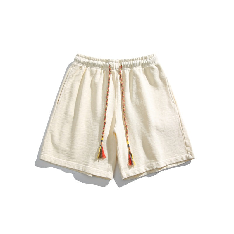 Cream-yellow knit shorts flat lay with elastic waist and braided multicolor tassel drawstring