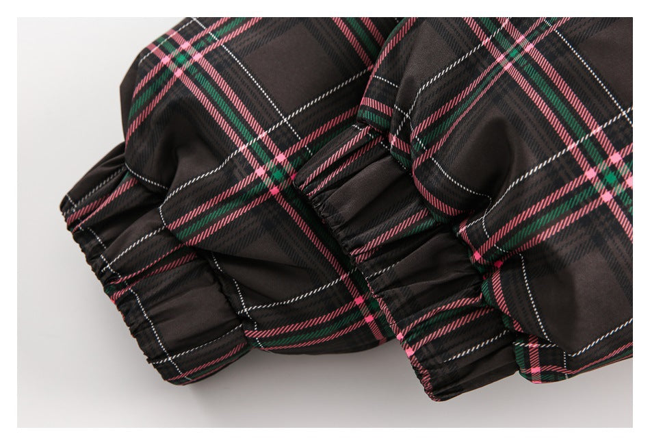 Close-up of gathered elastic edges on a dark plaid garment with pink, green, and white stripes.