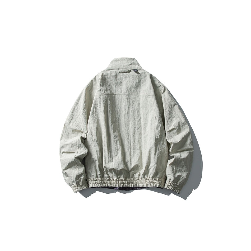 Back view of a light gray jacket with a stand collar, gathered cuffs, and an elasticated hem.