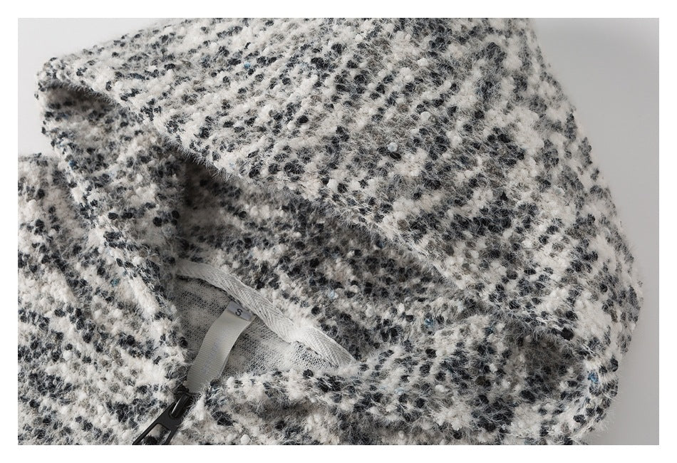 Close-up of a black-and-white fuzzy garment with a black zipper and a small size S label.