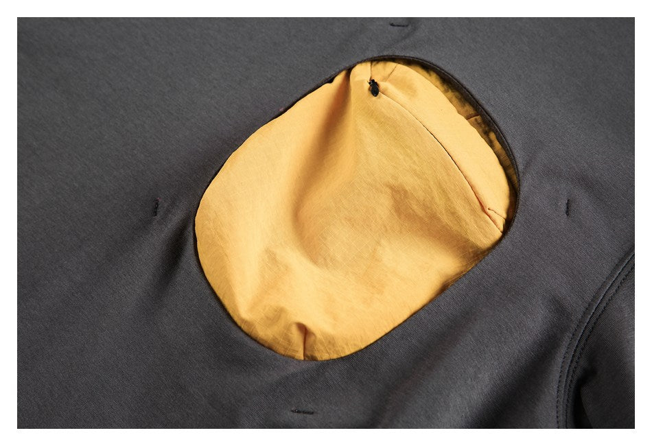 Close-up of a rounded opening in charcoal fabric, showing mustard-yellow lining and a small zipper.