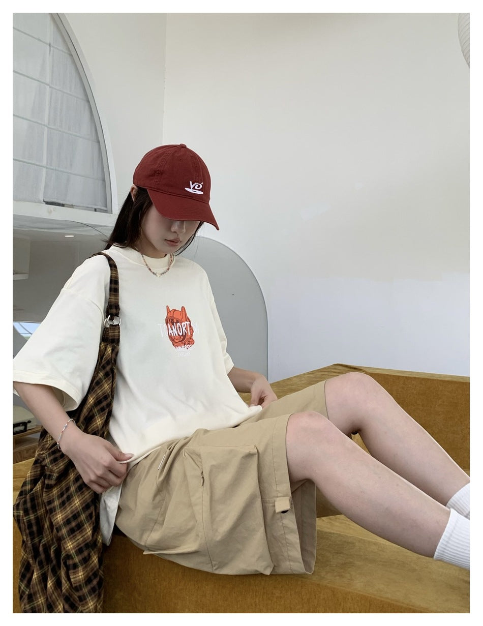 Model seated wearing beige cargo shorts with an elastic waist and large side pockets.