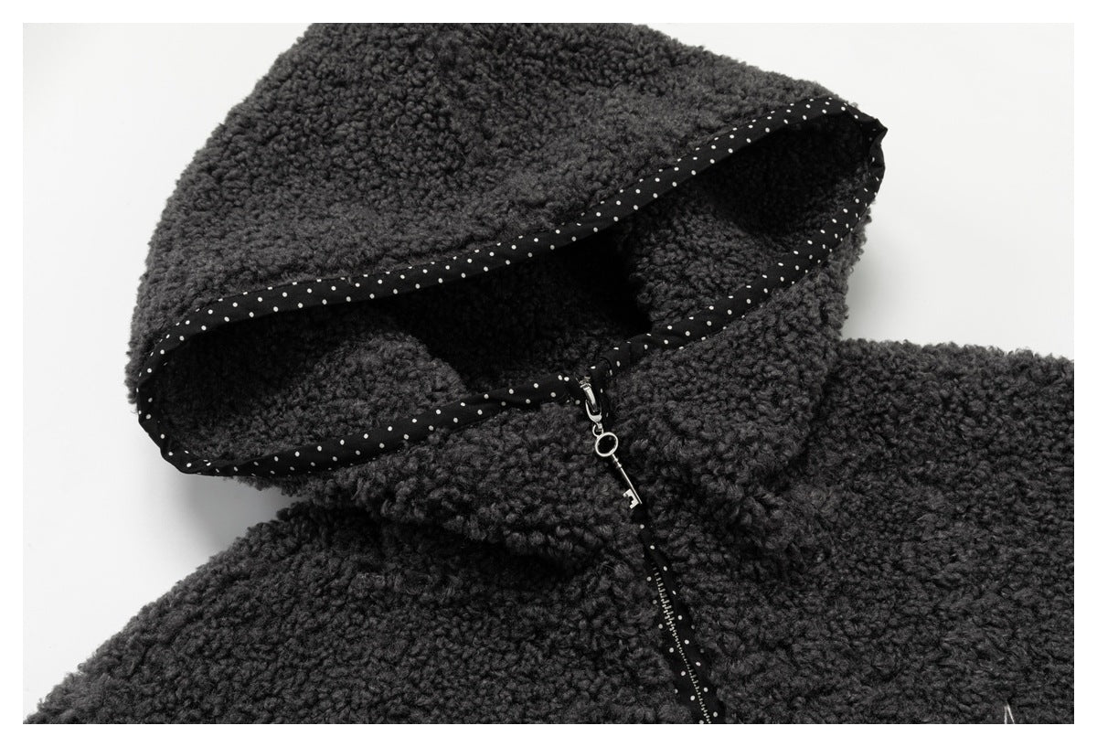 Close-up of a charcoal nubby hood with dotted black trim and a zipper pull.