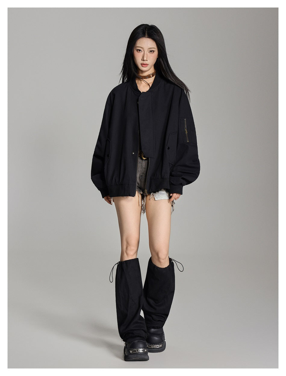 Full-length model wearing an oversized black bomber jacket with front flap, snap pockets, and a zippered sleeve pocket.