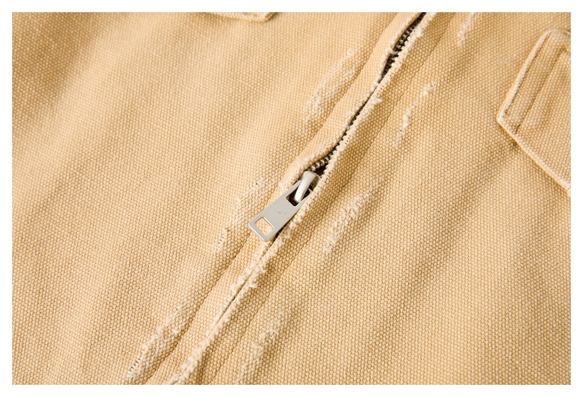 Close-up of the jacket's metal zipper against textured tan fabric.