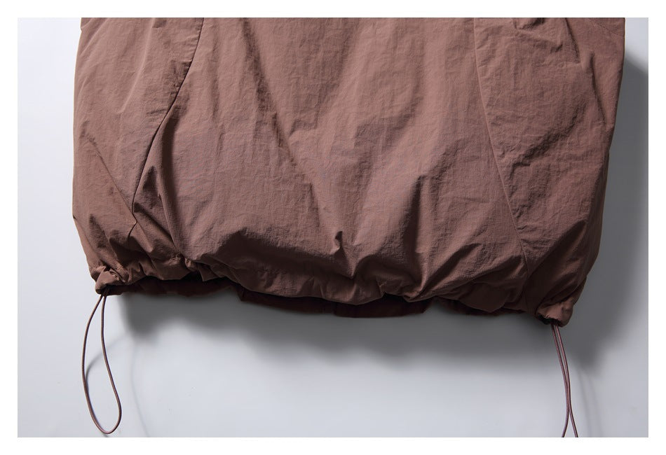Close-up of the brown jacket's gathered hem with adjustable drawcords at both sides.