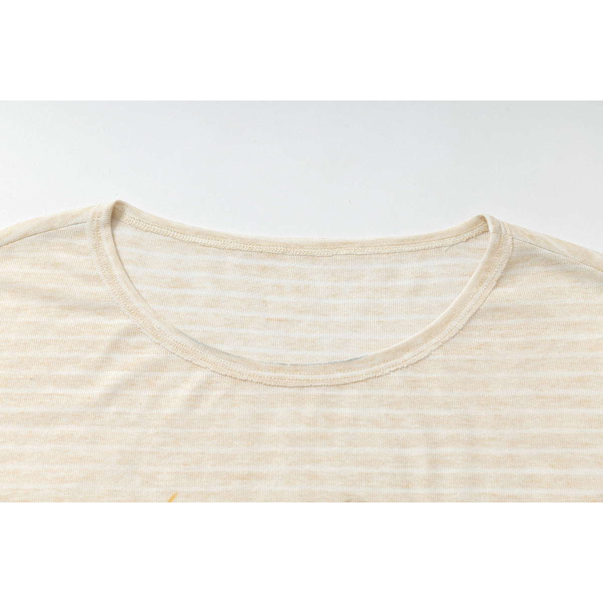 Close-up of the rounded neckline and subtle cream stripes on a light beige T-shirt.