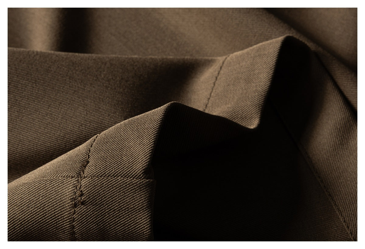 Close-up of brown trouser fabric folds and stitched seams.
