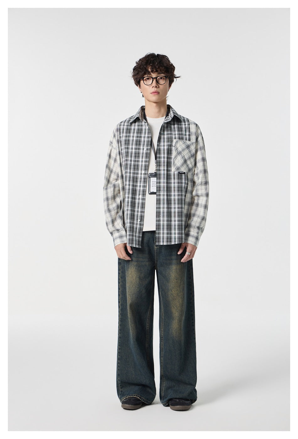 Full-length front view of a model wearing a black and cream mixed-plaid shirt over a white tee.