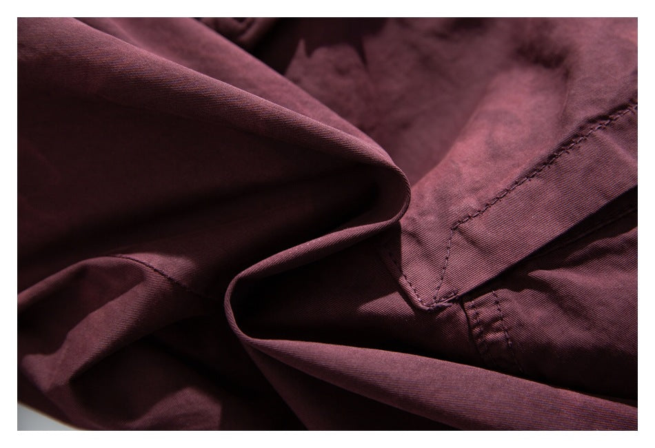 Macro view of burgundy fabric folds and a stitched garment seam.