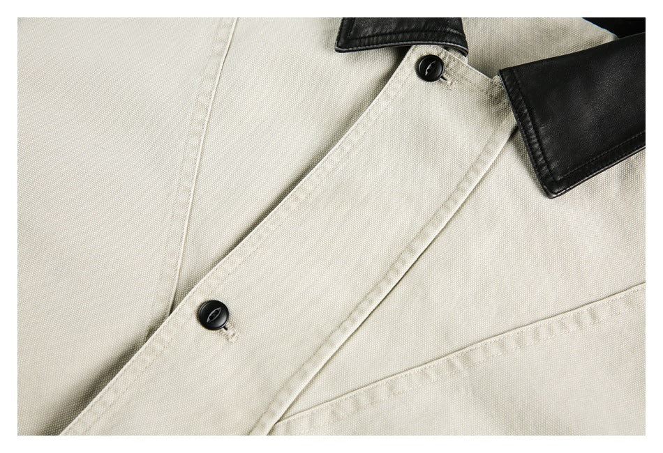Close-up of a cream jacket's diagonal front placket with two black buttons and a black collar edge.