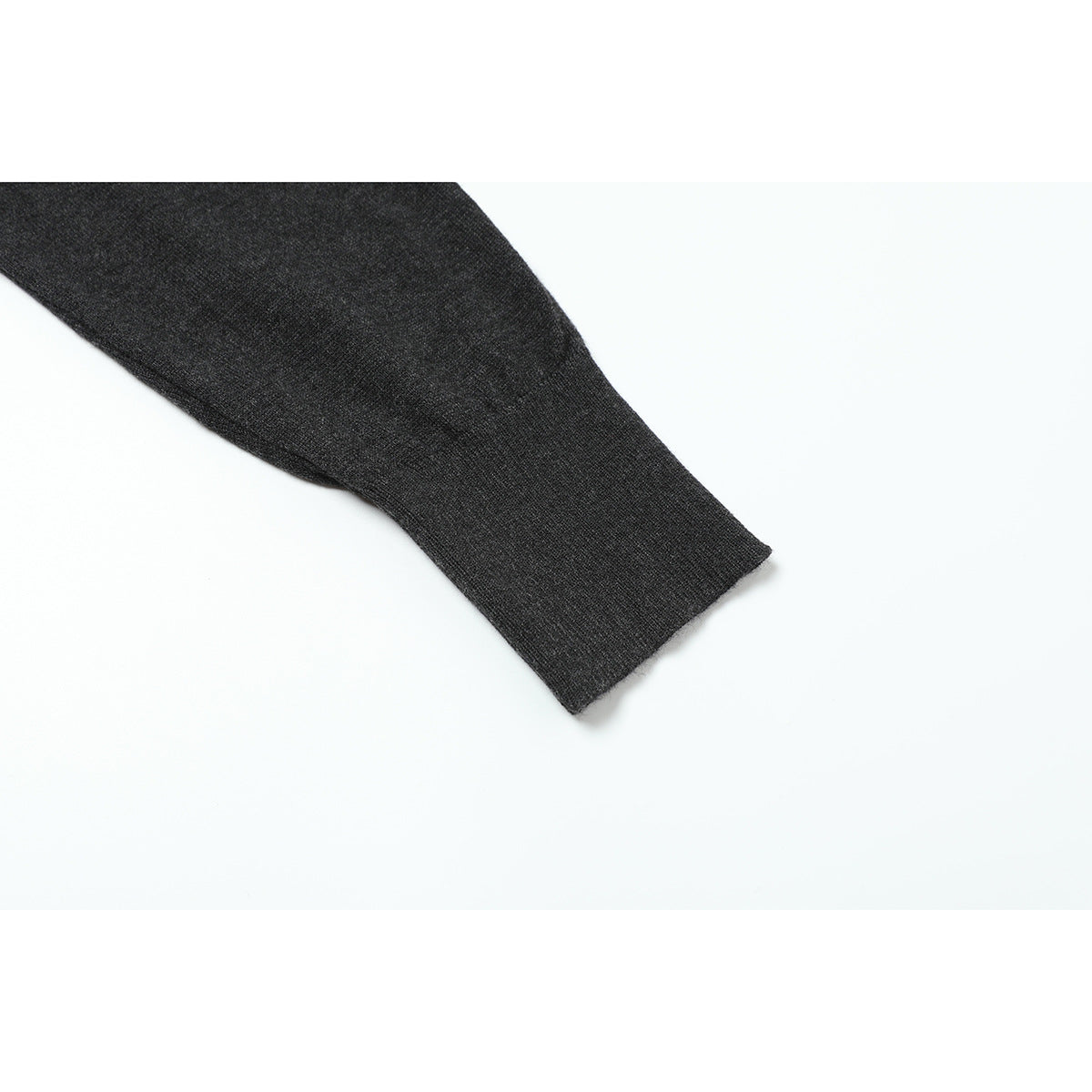 Close-up of a charcoal knit sleeve ending in a plain cuff.