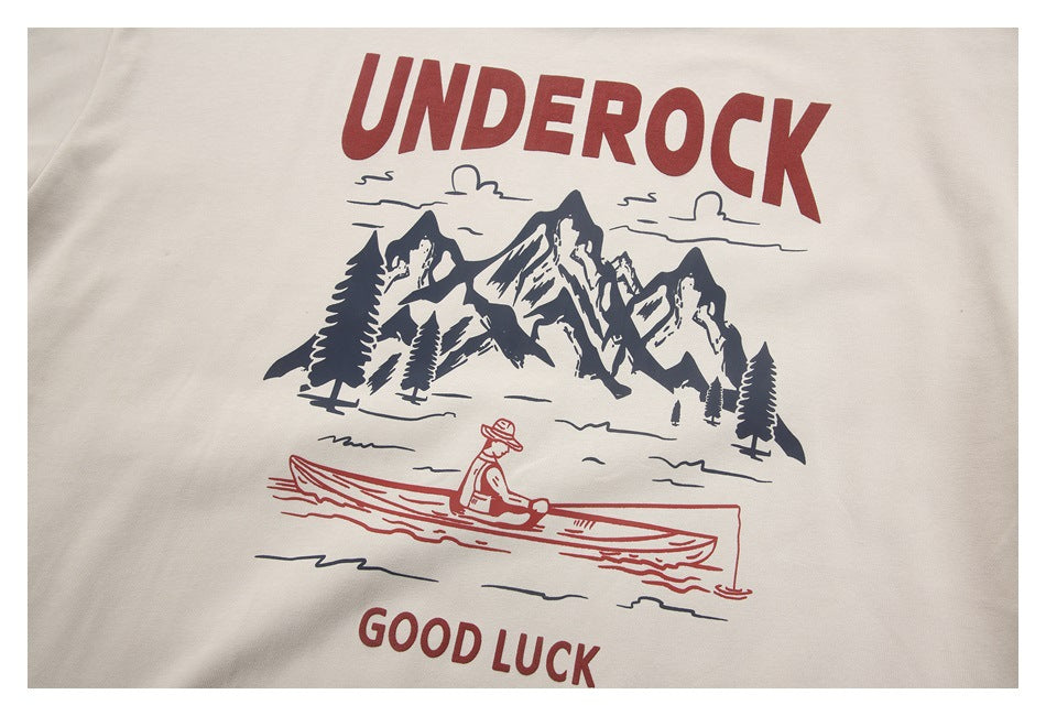 Beige shirt graphic with red UNDEROCK and GOOD LUCK lettering, mountains, trees, and a person rowing.