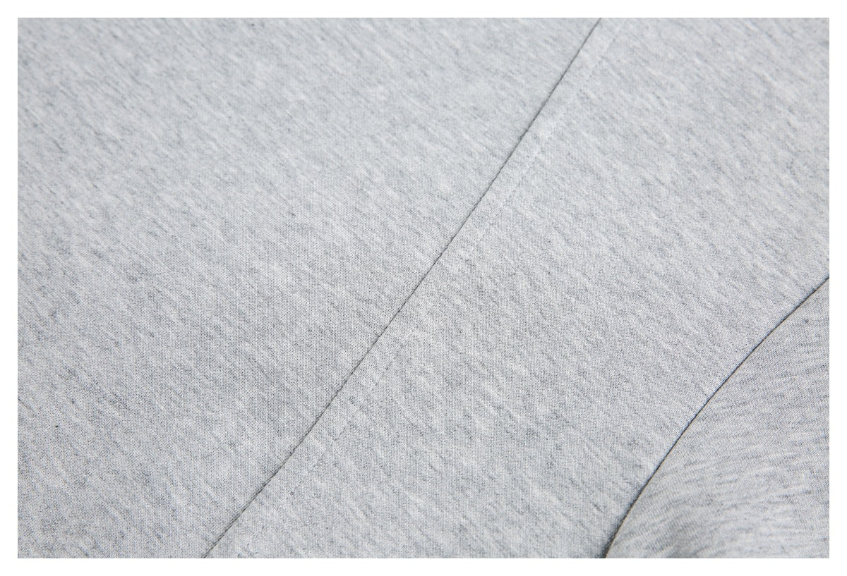 Close-up of light gray heathered knit fabric showing two diagonal seams.