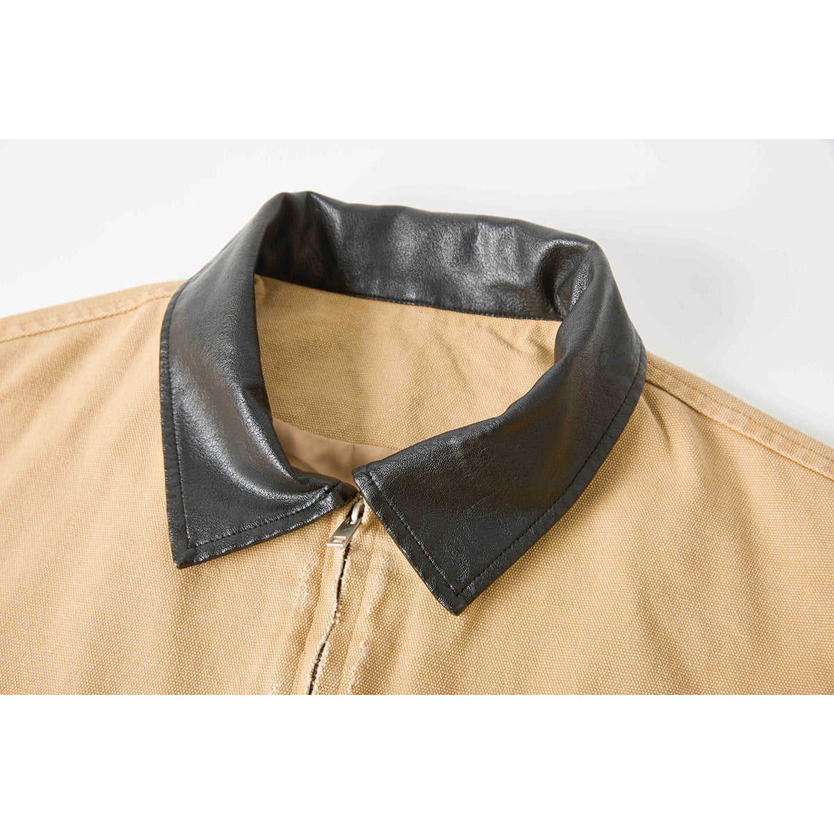 Close-up of a tan jacket's black pointed collar and front zipper.