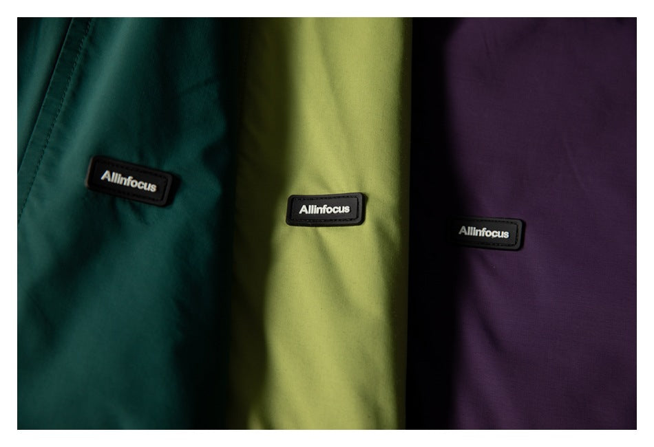 Dark teal, lime green, and purple garment panels, each with a small black brand patch.