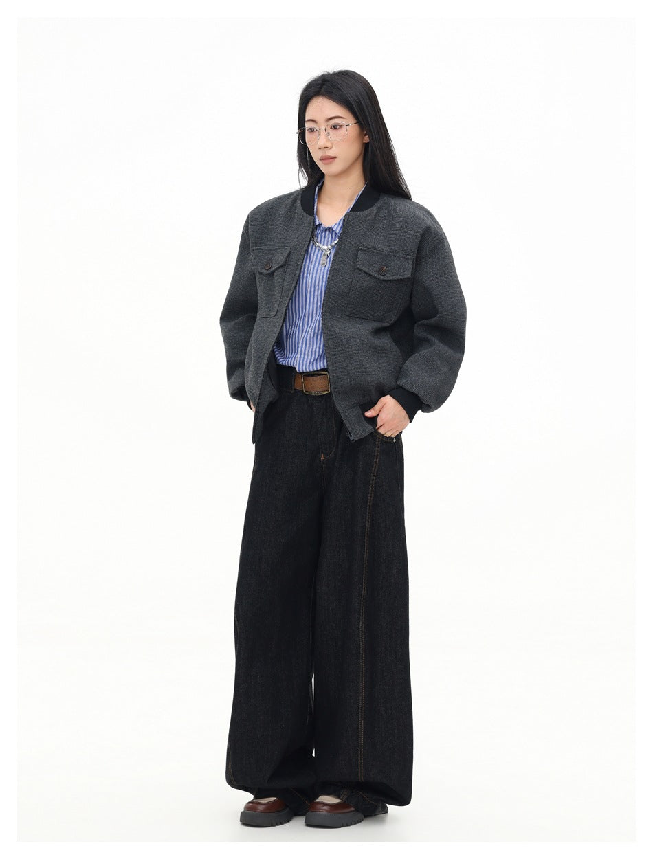Three-quarter view of a model wearing an open charcoal plaid bomber jacket with black ribbed trim and flap chest pockets.