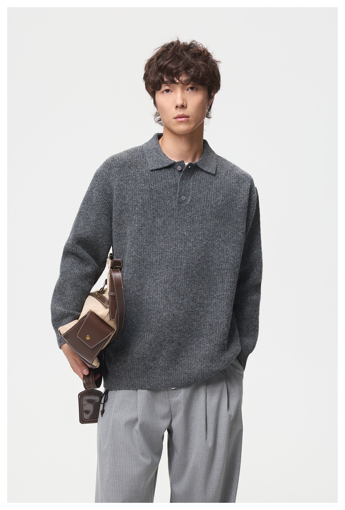 Front view of a model wearing a charcoal gray knit polo with a collar and three-button placket.
