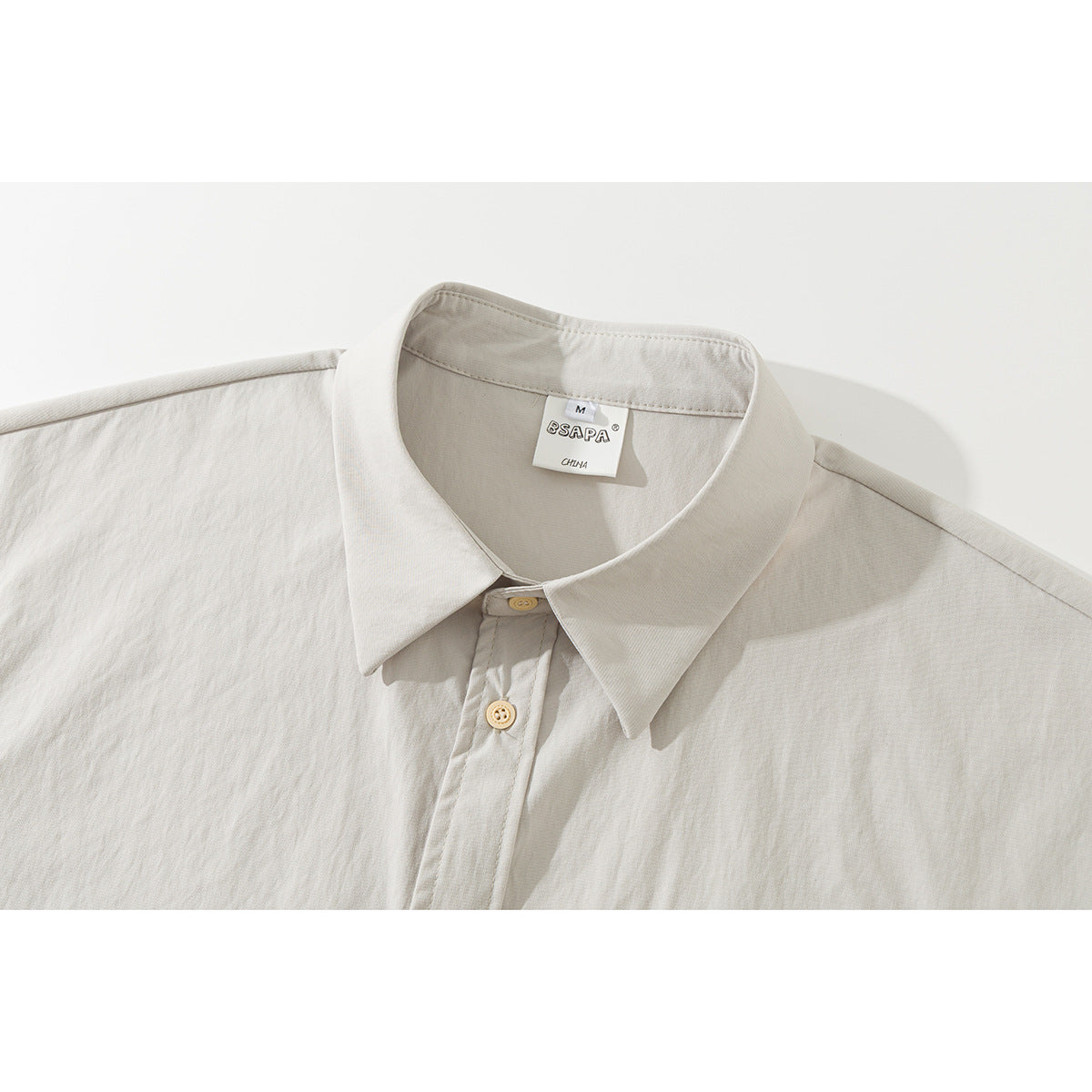 Close-up of an off-white short-sleeve shirt collar, neckline label, and top buttons.