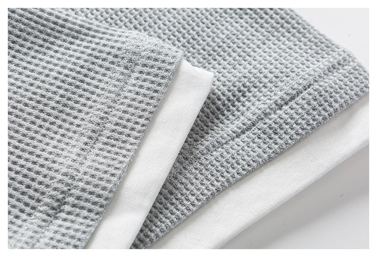 Close-up of gray waffle-knit garment edges finished with white binding.