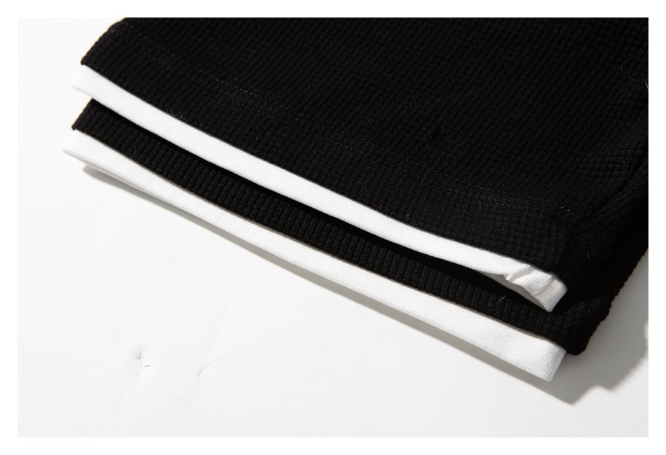 Folded black ribbed garment with contrasting white trim along the edges.