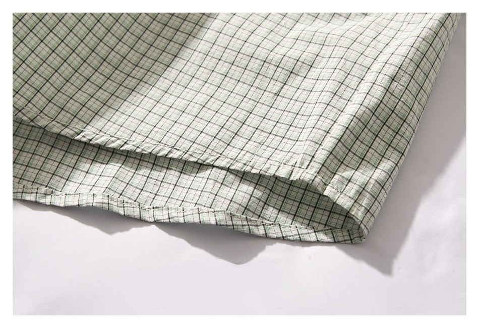 Close-up of a pale green and white plaid garment hem with visible stitching and a folded edge.