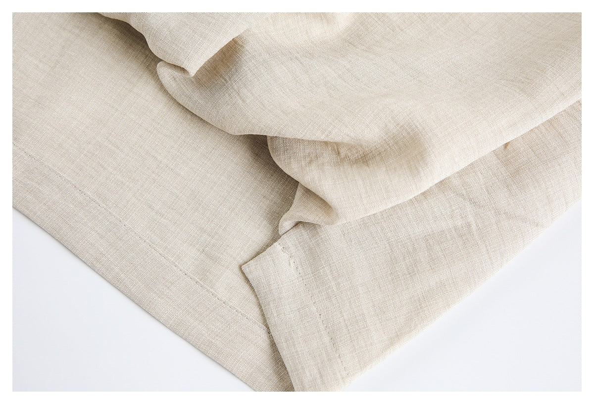 Close-up of folded ivory garment fabric with stitched edges and a curved seam.