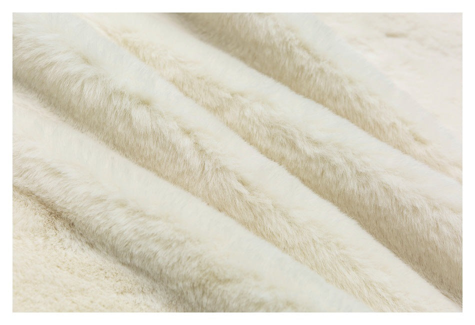 Close-up of soft-looking cream fabric with a plush, fuzzy surface and flowing folds.