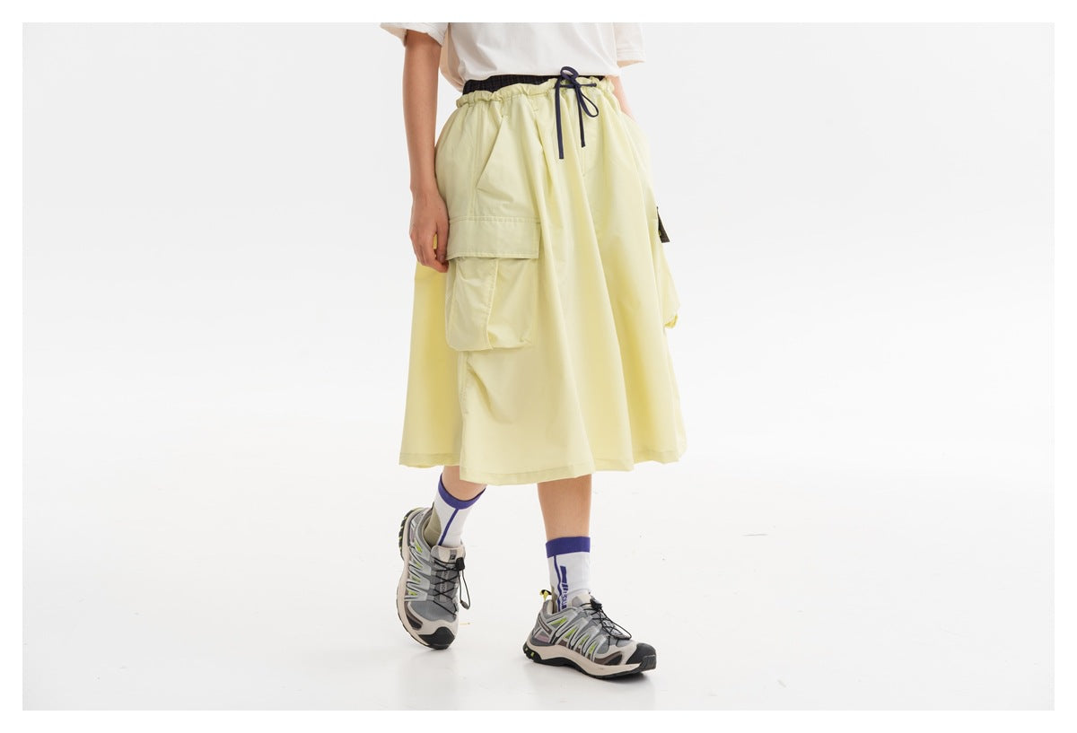Side view of a model wearing pale yellow wide-leg cropped pants with an elastic waist and flap cargo pockets.