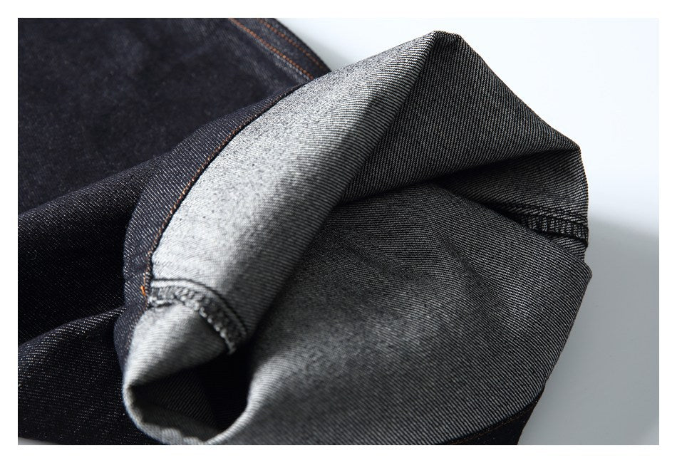 Folded dark denim reveals its gray reverse side and stitched edge.