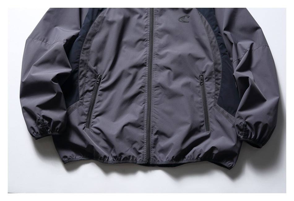 Lower front of a charcoal-gray jacket with dark side panels, a full-length zipper, two zip pockets and elastic cuffs.