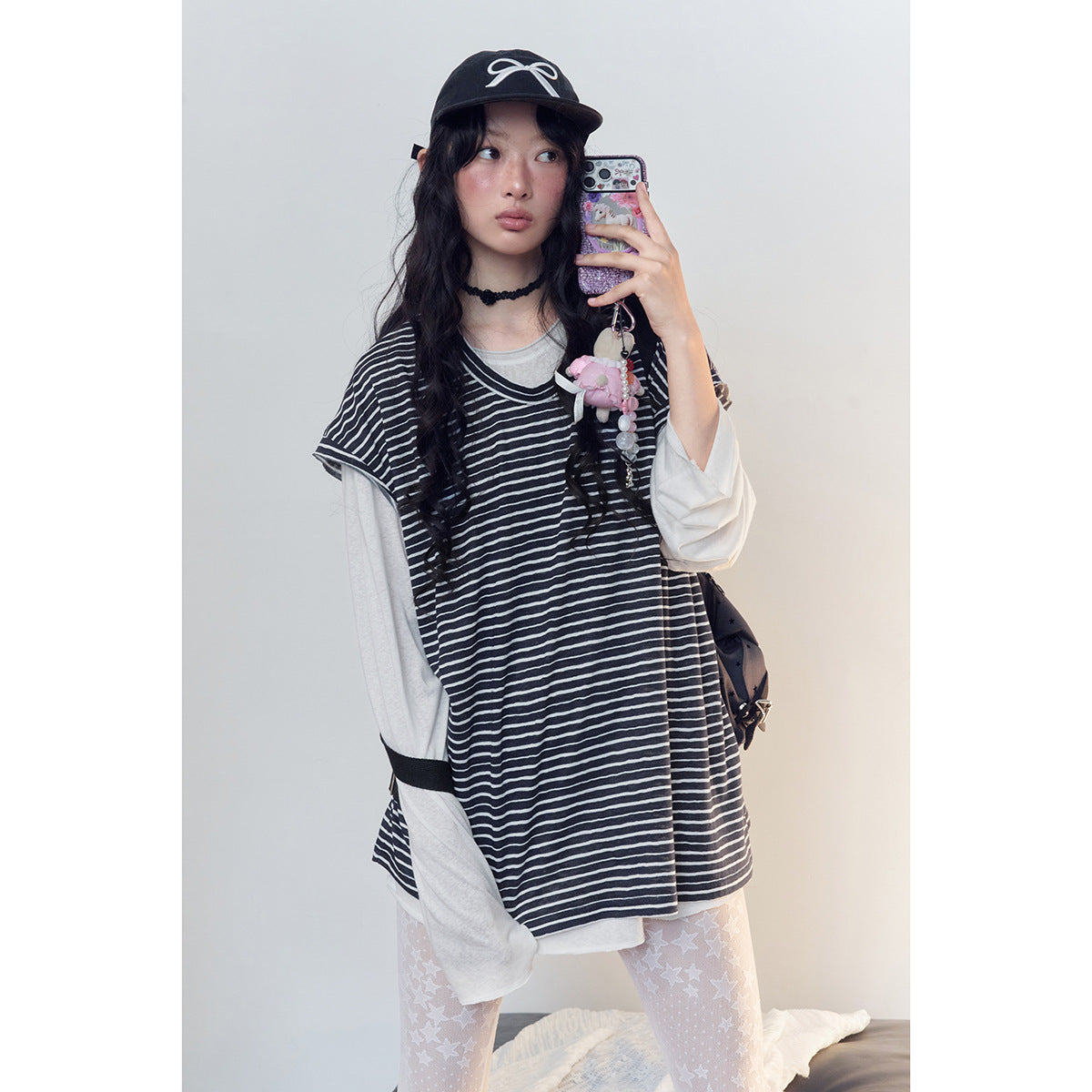 Model wearing an oversized black-and-white striped short-sleeve top over a white long-sleeve shirt.
