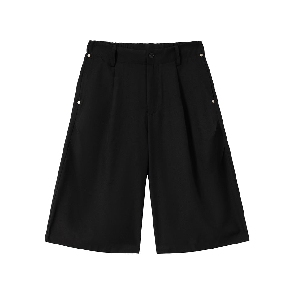 Black knee-length wide-leg pleated shorts with rivet side pockets, front view flat lay