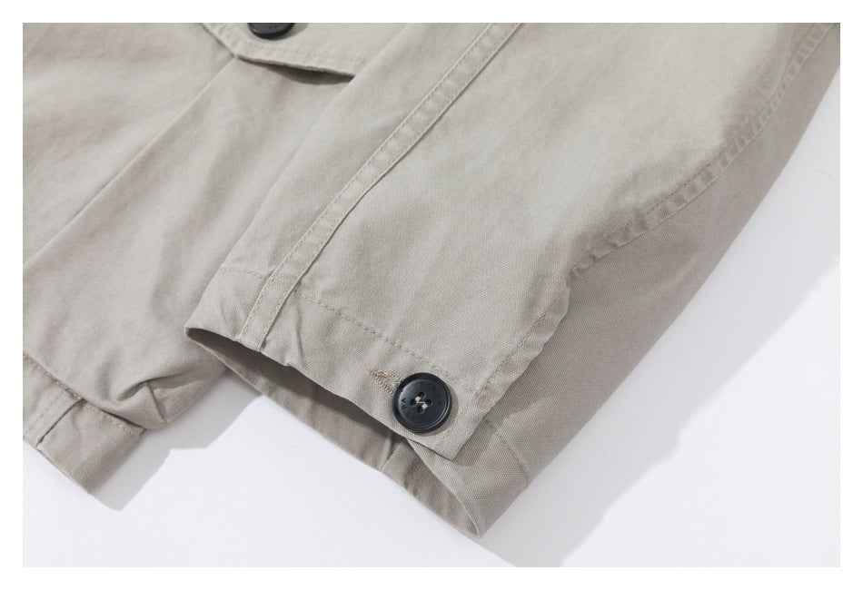 Close-up of a beige garment cuff with a dark button, seam, and stitched edge.