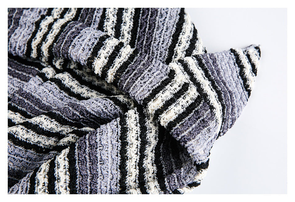 Close-up showing the textured gray, black, and cream stripes and a sleeve of the pullover.